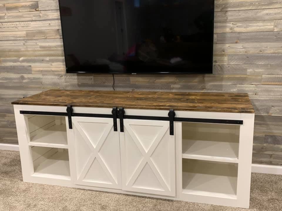 Custom white entertainment stand with sliding barn-style doors and a stained wood top
