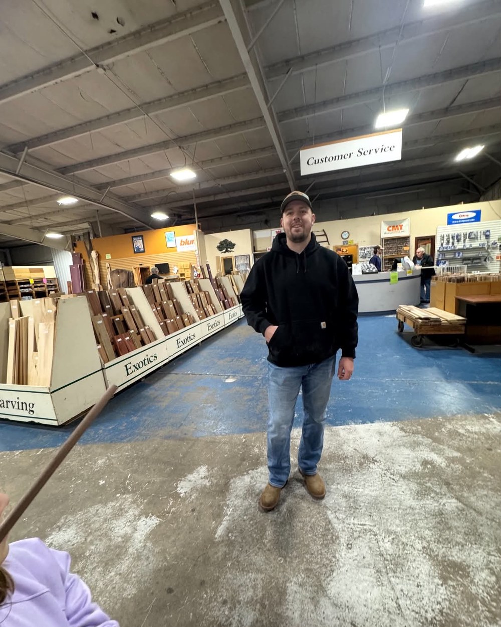 Alex Hulsmeyer standing among racks of hardwood at the lumber yard